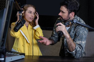 Neşeli adam ve kadın radyo stüdyosunda canlı yayında konuşuyor.