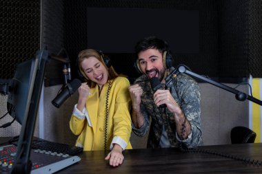 Young man and woman presenting in radio station hosting live radio show clipart