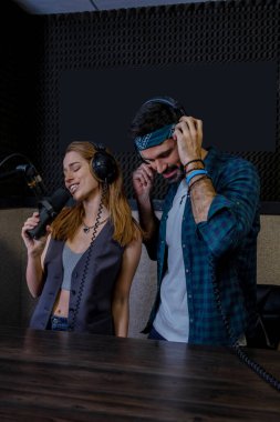 Hippi erkek ve kadın playback şarkıcıları stüdyoda kayıt yapıyor.