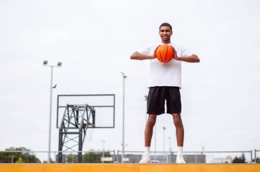 Basketbolcu. Uzun boylu, yakışıklı, elinde top olan kendine güvenen bir genç.