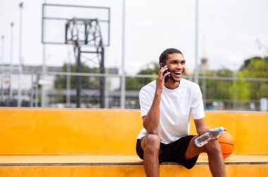 Genç sporcu. Elinde telefon olan genç sporcu kendinden emin görünüyor.