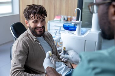 Kliniğe diş yerleştirmeden önce diş muayenesi sırasında hasta olan erkek stomatolog.