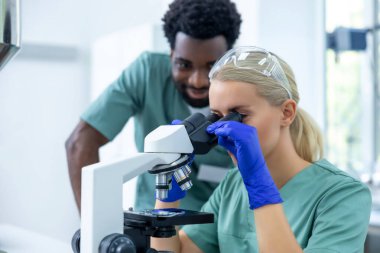 Aşı geliştirmek için mikroskop üzerinde çalışan biyokimyasal araştırma ekibi ilaç etiketleme alanında çalışıyor.