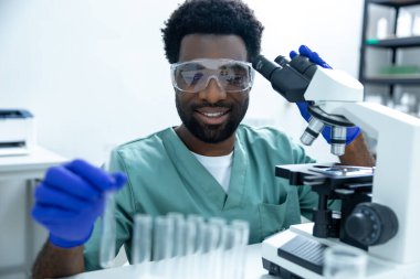 Laboratuvarda çalışan doktor bilim adamı aşıyı test etmek ve tıp kariyeri için virüs örneklerini incelemek için teknoloji ve mikroskop kullanıyor.