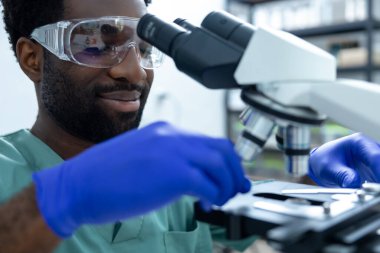 Laboratuvarda çalışan doktor bilim adamı aşıyı test etmek ve tıp kariyeri için virüs örneklerini incelemek için teknoloji ve mikroskop kullanıyor.