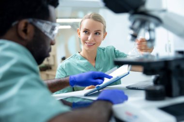 Çok kültürlü bir kadın ve erkek eczacılık araştırmaları için birlikte çalışıyorlar.