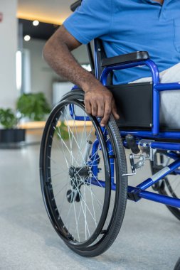 Tekerlekli sandalyedeki adam. Tekerlekli sandalyede oturan mavi tişörtlü bir adama yaklaş.