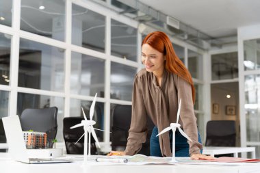 Wind turbine project. Young female specialist working on a wind turbine project and looking involved clipart