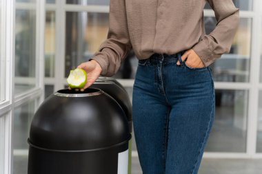 Organik atık. Kot pantolonlu kadın organik atıkları uygun konteynıra atıyor.