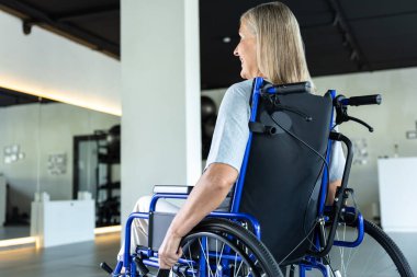 Tekerlekli sandalyedeki yetişkin kadın hastanede rehabilitasyon görüyor.
