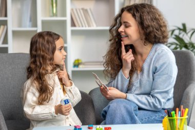 Konuşma terapisi. Güzel, uzun saçlı kız doktorla konuşma terapisi yapıyor.
