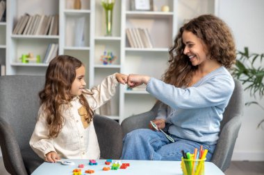 Konuşma terapisi. Güzel, uzun saçlı kız doktorla konuşma terapisi yapıyor.