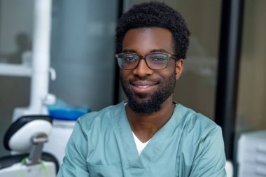 Modern klinikteki işyerindeki yakışıklı Afrikalı Amerikalı dişçi.