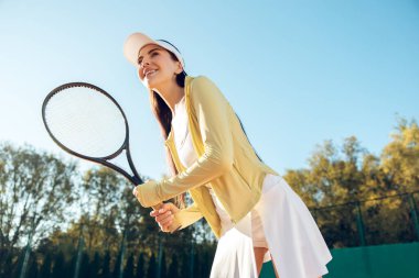 Tenis oyuncusu. Uzun saçlı, beyaz şapkalı, tenis oynayan genç bir kadın.