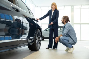 Yeni araba modeli. Kadın galeri temsilcisi müşteriye yeni bir araba modeli gösteriyor