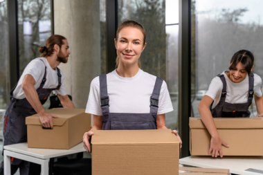 Paketi olan genç bir kadın. Elinde bir paketle gülümseyen kadın ambalaj merkezi çalışanı