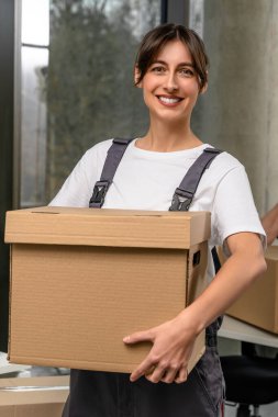 Teslimat servisi. Gülümseyen siyah saçlı kız göndermeden önce elinde bir paket tutuyor.