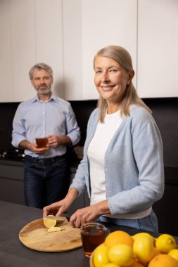 Neşeli Kafkasyalı son sınıf çifti mutfakta meyve ve çayla birlikte sağlıklı bir kahvaltı hazırlıyorlar.