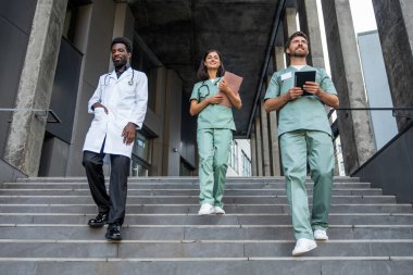 Doktorlar. Laboratuvar önlüklü doktorlar merdivenlerde kendinden emin görünüyorlar.