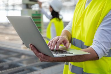 Erkek mühendis iş başında. Bilgisayarlı genç erkek mühendis inşaat alanındaki parametreleri kontrol ediyor.