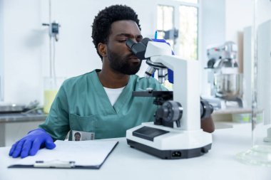 Afrika kökenli Amerikalı bilim adamı mikroskop laboratuvarında aşı geliştirme üzerine araştırma yapıyor.