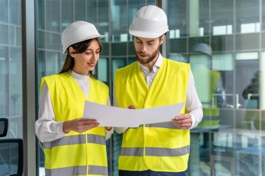 Sürdürülebilirlik projesi. Sarı yelekli iki genç mühendis yeni sürdürülebilirlik projesini tartışıyor.