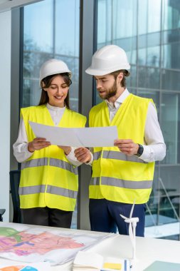 Sürdürülebilirlik projesi. Sarı yelekli iki genç mühendis yeni sürdürülebilirlik projesini tartışıyor.