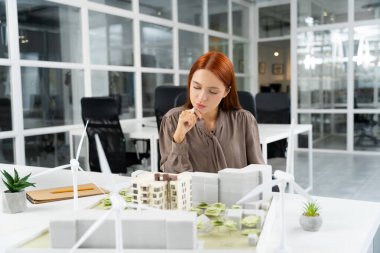 Proje çalışması. Modern ofiste çalışan kızıl, genç bir kadın.