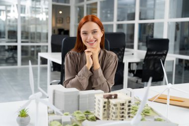 - Mimar. Genç beyaz kadın mimar ofiste bir bina modeli üzerinde çalışıyor.