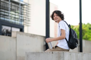 Dersten sonra. Koyu saçlı genç derslerden sonra bloklarda oturup dinleniyor.