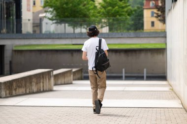Stree 'deki öğrenci. Uzun boylu, esmer, beyaz bir öğrenci. Sırt çantasıyla sokakta yürüyor.