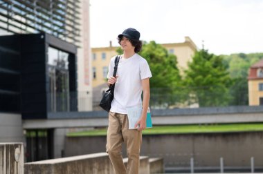 Dersten sonra. Uzun boylu şapkalı ve beyaz tişörtlü bir öğrenci okuduktan sonra evine gidiyor.