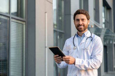 Erkek doktor. Elinde tablet olan laboratuvar önlüklü kızıl adam kararlı görünüyor.