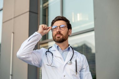 Erkek doktor. Gözlüklü ve laboratuvar önlüklü kararlı ve kendinden emin bir genç.