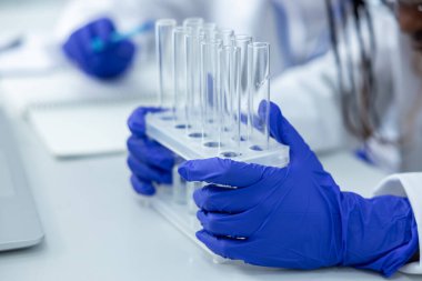 Laboratuvarda elinde pipetlerle klinikteki aşı geliştirme aşıları üzerinde test yapan tanınamayan bir tıp kadını var.
