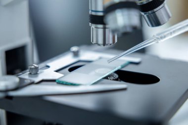 - Bilim. Merceğin altında bir test bardağıyla mikroskobu kapat