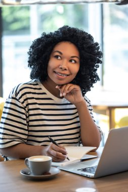 Fikir yazmak. Masada oturan ve not defterine not alan bir kadın.