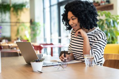 Yoğun bir gün. Kıvırcık saçlı, serbest meslek sahibi, dizüstü bilgisayarda çalışan ve meşgul görünen bir kadın.