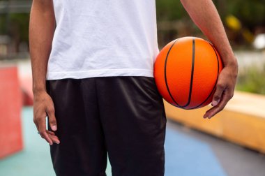 Basketbolcu. Elinde turuncu bir top tutan adama yaklaş.