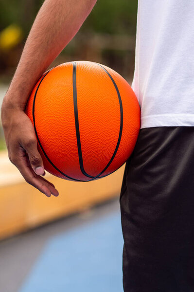 Баскетболист. Крупный план человека, держащего в руках оранжевый шар