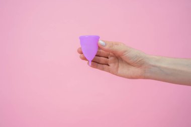 Adet görmek için çevreye duyarlı silikon bardaklar gösteren anonim bir kadın. Pembe arka planda izole edilmiş sıfır atık yaşam tarzı için alternatif hijyen.