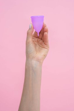 Adet görmek için çevreye duyarlı silikon bardaklar gösteren anonim bir kadın. Pembe arka planda izole edilmiş sıfır atık yaşam tarzı için alternatif hijyen.