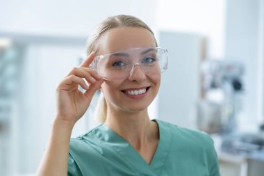 Koruyucu gözlüklü kadın doktor modern bilim laboratuarında tıp araştırmaları yapıyor.