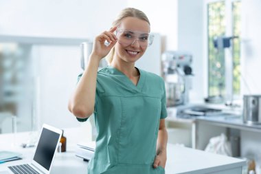 Koruyucu gözlüklü kadın doktor modern bilim laboratuarında tıp araştırmaları yapıyor.