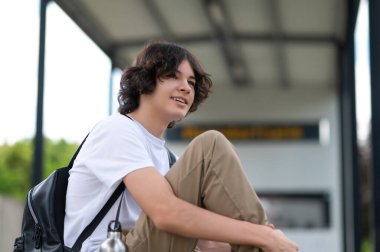 Dersten sonra. Koyu saçlı genç derslerden sonra bloklarda oturup dinleniyor.