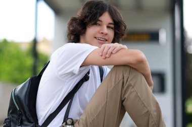 Dersten sonra. Koyu saçlı genç derslerden sonra bloklarda oturup dinleniyor.