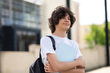 Dersten sonra. Elinde kitabı olan koyu renk saçlı bir ergen.