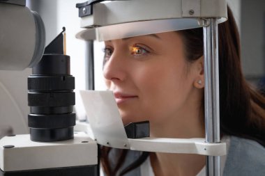 Yetişkin bir kadın profesyonel göz muayenesi ve görme tedavisi için hastanede göz doktorunu ziyaret ediyor.