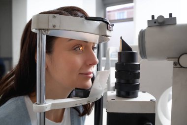 Optometri kliniğindeki kadın hasta görüşünü uygun gözlük ve lens düzeltmesi için ölçüyor.