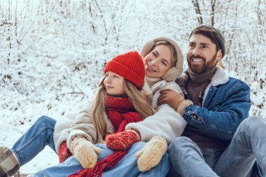 Kış günü. Genç sevimli aile ormanda kış gününün tadını çıkarıyor.